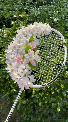 a tennis racquet with flowers on it in front of bushes and shrubbery