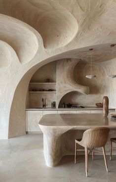 a kitchen with an oval table surrounded by white walls and stone arches on the ceiling