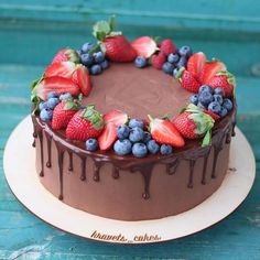 a chocolate cake topped with fresh strawberries and blueberries