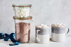 three mugs filled with hot chocolate and marshmallows next to each other