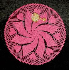 a crocheted doily on the ground with a small flower in it's center