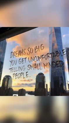 a window with writing on it in front of a cityscape that reads, dreams so big you get uncomfortableable telling small minds people