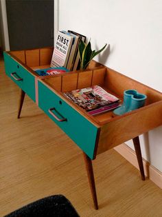 a wooden table with magazines and cups on it in front of a white wall next to a black rug