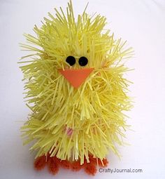 a yellow toy with black eyes sitting on a white surface