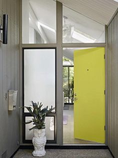 an open door leading into a room with a plant in the corner and a mirror on the wall