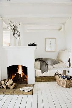 a living room with a fire place in the center and white furniture on the other side