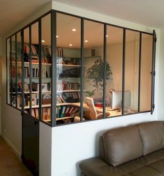 a living room filled with furniture next to a window covered in bookshelves on the wall