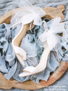 a pair of high heeled shoes sitting on top of a pile of blue fabric