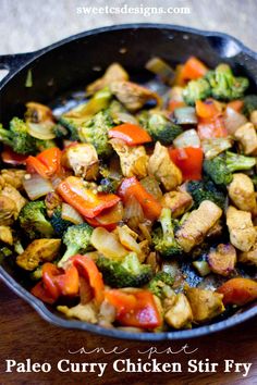 a pan filled with chicken and veggies on top of a wooden table