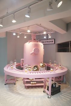 a pink table with lots of cupcakes on it and a large tank in the middle