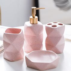 three pink bathroom accessories on a white table