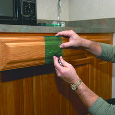 a man holding a green piece of paper in his hand while standing next to a kitchen counter