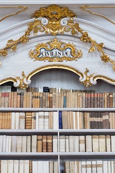 an ornately decorated bookshelf filled with lots of books in front of a white wall