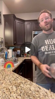 a man standing in front of a kitchen counter holding a pan with food on it