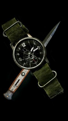 a watch that is sitting on top of a leather strap with a knife in front of it