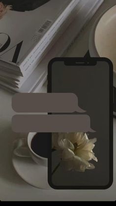 a white flower sitting on top of a table next to a book