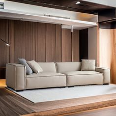 a white couch sitting on top of a wooden floor next to a wall with wood paneling