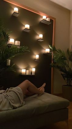 a woman laying on top of a bed in front of a wall filled with lights