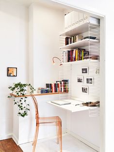 a white desk and chair in a small room with bookshelves on the wall