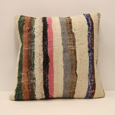 a multicolored striped pillow sitting on top of a white table next to a wall