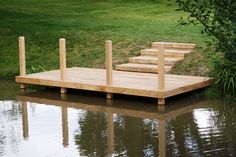 a wooden dock sitting on top of a body of water next to a lush green field