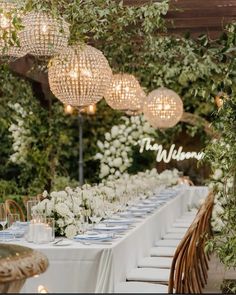 a long table is set with white flowers and greenery for an outdoor wedding reception