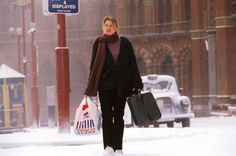 a woman walking in the snow with her luggage