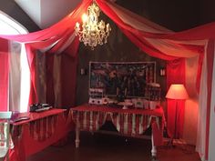 the room is decorated with red and white drapes, chandelier, table cloths, and pictures