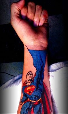 a man with a superman tattoo on his arm holding up the fist and hand sign