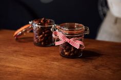 two jars filled with nuts on top of a wooden table