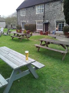 picnic tables and benches in front of an old stone building with a beer mug on the table