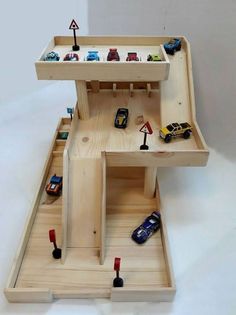 a wooden toy car garage with cars and trucks in it's trays on the floor