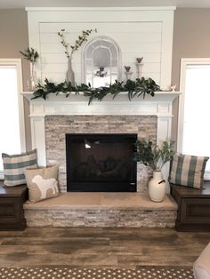 the fireplace is decorated with greenery and pillows