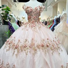 a pink ball gown on display in a room filled with mannequins and dresses