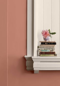 a vase filled with pink flowers sitting on top of a window sill next to books