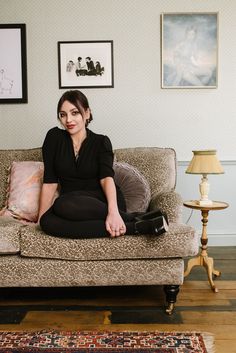 a woman sitting on top of a couch next to a lamp