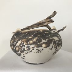 a white and black vase with a branch sticking out of it