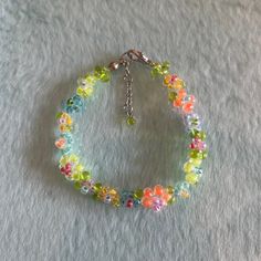 a bracelet with multicolored glass beads and silver clasps on a white surface