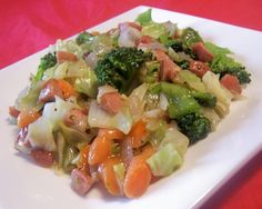 a white plate topped with broccoli, carrots and other vegetables on top of a red table cloth