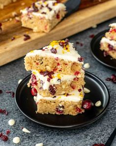 three pieces of cake on black plates with cranberry toppings and white frosting