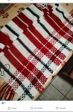 a red and white knitted blanket sitting on top of a tiled floor