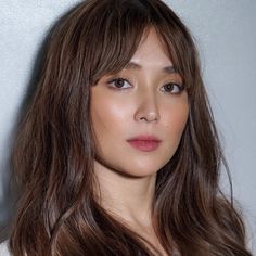 a woman with long brown hair is posing for the camera and looking at the camera