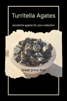 a white bowl filled with lots of rocks on top of a wooden table next to a sign