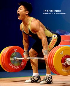 a man holding a barbell on top of a wooden floor