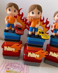 three figurines sitting on top of each other in front of a fire truck