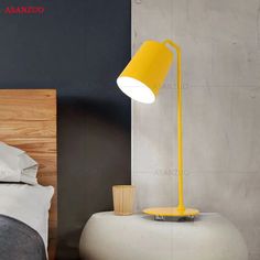 a yellow lamp sitting on top of a table next to a bed