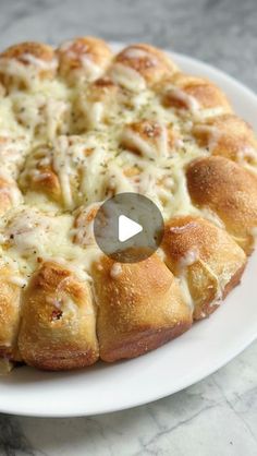 a white plate topped with a cheesy bread bun on top of a table