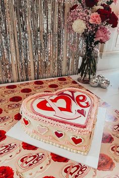 a heart shaped cake sitting on top of a table next to a vase filled with flowers