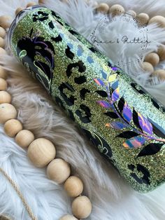 a green and black leopard print tumbler with wooden bead necklace on white fur