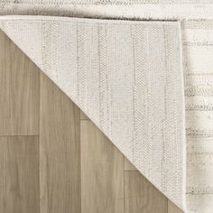 a white rug on top of a wood floor next to a wooden flooring board